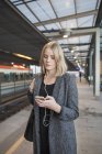 Giovane donna che utilizza smartphone sulla stazione della metropolitana — Foto stock