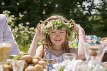 Portrait of girl adjusting flower wreath, focus on foreground — Stock Photo