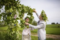 Жінка і чоловік влаштовують квіткові вінки для літніх святкувань — стокове фото