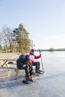 Зрелая женщина и мужчина катаются на коньках по замерзшему озеру — стоковое фото