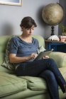 Mujer que trabaja en casa, usando tableta digital - foto de stock