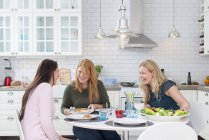 Три смеющихся женщины за кухонным столом — стоковое фото