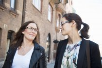 Two women walking along street and looking at each other — Stock Photo