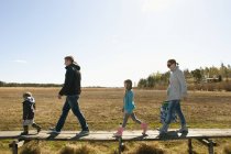 Visão lateral da família caminhando no campo, foco seletivo — Fotografia de Stock