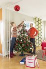 Mature couple decorating Christmas tree in living room — Stock Photo