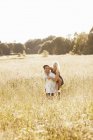 Young couple riding piggyback in meadow — Stock Photo