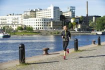 Woman in sportswear running along embankment — Stock Photo