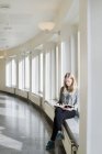 Giovane donna che legge libro alla sala universitaria — Foto stock