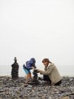 Мать и дочь строят каирн на пляже — стоковое фото