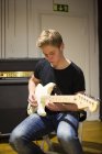 Молодий чоловік грає на гітарі у вітальні — стокове фото