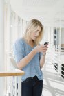 Junge Frau benutzt Smartphone in Uni-Gebäude — Stockfoto