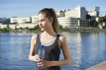Donna in piedi con bottiglia d'acqua in mano — Foto stock