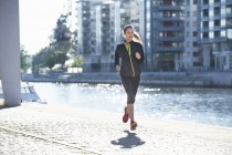 Mulher em sportswear correndo ao longo aterro — Fotografia de Stock