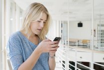 Junge Frau nutzt Smartphone an der Universität — Stockfoto