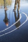 Ausgeschnittener Blick auf reife Männer beim Schlittschuhlaufen auf gefrorenem See — Stockfoto