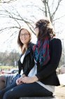 Дві жінки сидять в парку і посміхаються — стокове фото