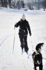 Junge Frau beim Skifahren mit Hund in Schweden — Stockfoto