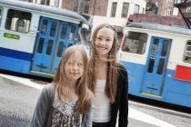 Dos chicas adolescentes mirando a la cámara contra el tranvía, enfoque selectivo - foto de stock