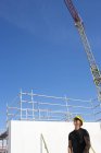 Trabalhador da construção em pé no canteiro de obras e olhando para cima — Fotografia de Stock