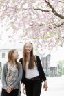 Две девочки-подростки улыбаются, идя по улице, избирательно фокусируясь — стоковое фото