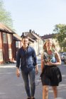 Веселая пара, идущая по улице, сфокусированная на переднем плане — стоковое фото