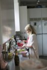 Mujer con tomates en cocina doméstica - foto de stock