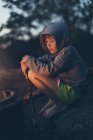 Garçon assis près du feu de camp, foyer sélectif — Photo de stock