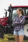 Agricultural worker standing in front of tractor, focus on foreground — Stock Photo