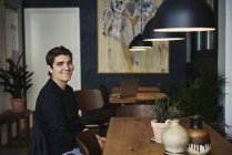 Молодой человек сидит в кафе, фокусируется на переднем плане — стоковое фото
