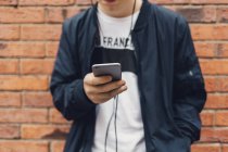 Обрізаний вид хлопчика-підлітка, який слухає музику на смартфоні, вибірковий фокус — стокове фото