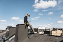 Roofer con smartphone en vacaciones de trabajo en Estocolmo, Suecia - foto de stock