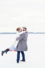 Visão lateral do jovem casal jogando na neve, foco seletivo — Fotografia de Stock
