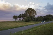 Auto guida lungo la strada sotto cielo coperto in Svezia — Foto stock