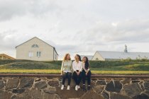 Três jovens mulheres sentadas na parede em Karlskrona, Suécia — Fotografia de Stock