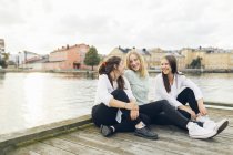Três jovens mulheres sentadas no cais em Karlskrona, Suécia — Fotografia de Stock