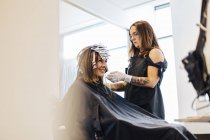 Hairdresser coloring clients hair in salon, selective focus — Stock Photo