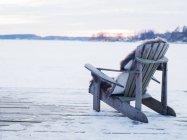 Cadeira de madeira no convés em neve em Sigtuna, Suécia — Fotografia de Stock