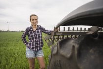 Agricultural worker standing next to tractor at field — Stock Photo