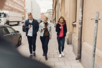 Підлітки йдуть по вулиці міста дивлячись на телефони — стокове фото
