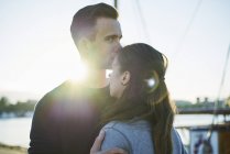 Young man kissing woman outdoors, focus on foreground — Stock Photo