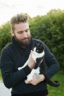 Молодой бородатый мужчина держит кота, сосредоточьтесь на переднем плане — стоковое фото