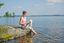 Mitte erwachsene Frau mit digitalem Tablet vor See in Finnland — Stockfoto