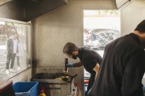 Chef cooking burgers on grill in food truck — Stock Photo