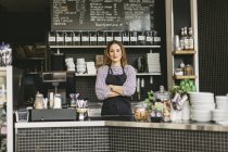 Portrait of barista looking at camera behind counter in cafe — Stock Photo