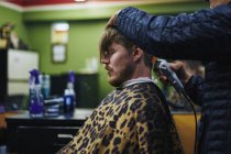 Мужчина стрижется в парикмахерской, фокусируется на переднем плане — стоковое фото