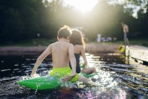 Brother and sister on pool toy at lake, selective focus — Stock Photo