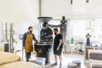 Due uomini che hanno conversazione contro la macchina torrefazione caffè — Foto stock