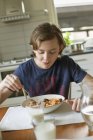 Хлопчик-підліток їсть сніданок вдома, зосередьтеся на передньому плані — стокове фото