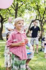 Niño sosteniendo bebida en el picnic de cumpleaños - foto de stock