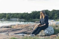 Взрослая женщина читает на открытом воздухе, фокусируется на переднем плане — стоковое фото